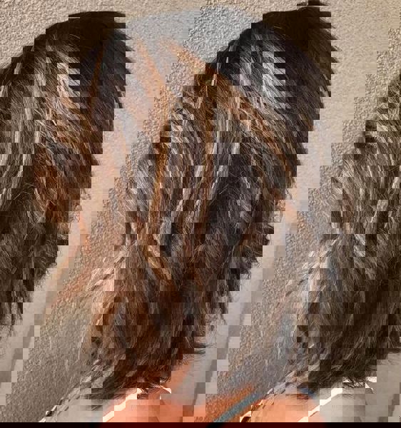 Średniej długości bob w odcieniu kasztanowym z złotymi refleksami w stylu balayage.