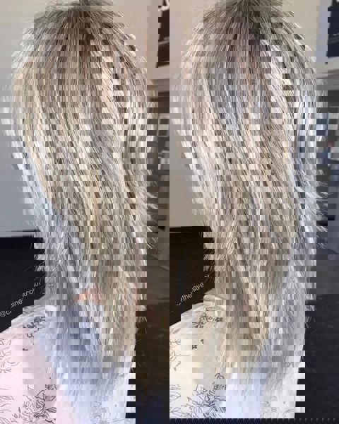 Średniej długości warstwowa fryzura o perłowo-blond kolorze, z lekkim efektem potargania