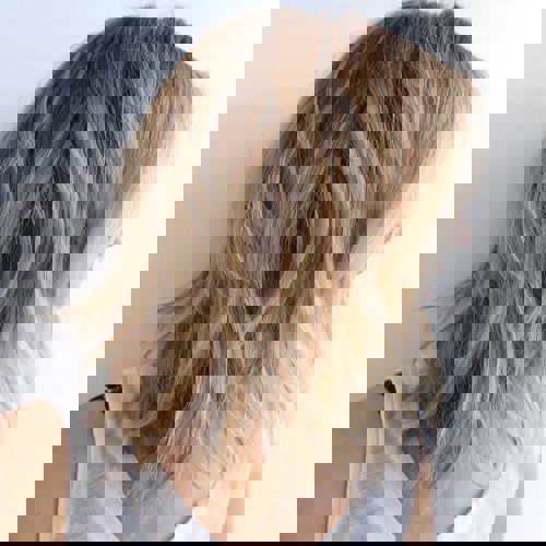 Twarzowo wyglądające fryzury o średniej długości w odcieniu średniego blondu z warstwowym cięciem.